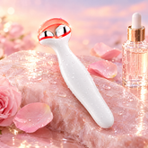GlowLift EMS facial massager glowing on a pink stone surface with rose petals